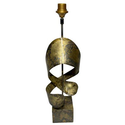Indická kovová lampa s jemnými zlatavými odlesky a zdobením připomínajícím elegantně vinuté kovové pásy.