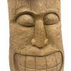 Tiki totem v podobě hlavy, precizně vyřezaný z teakového dřeva, umístěný na podstavci.